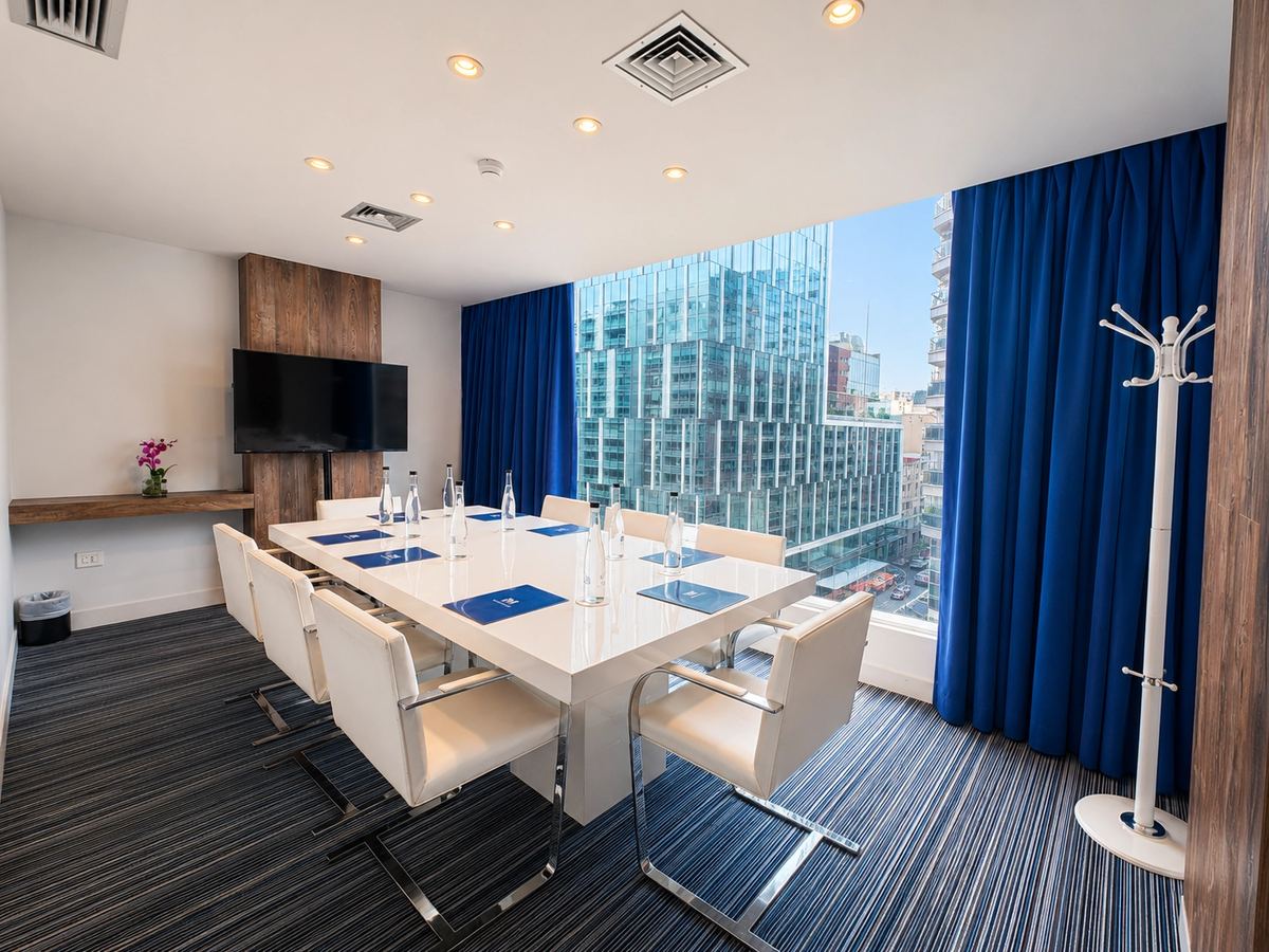 Boardroom with a white table, a screen and blue curtains
